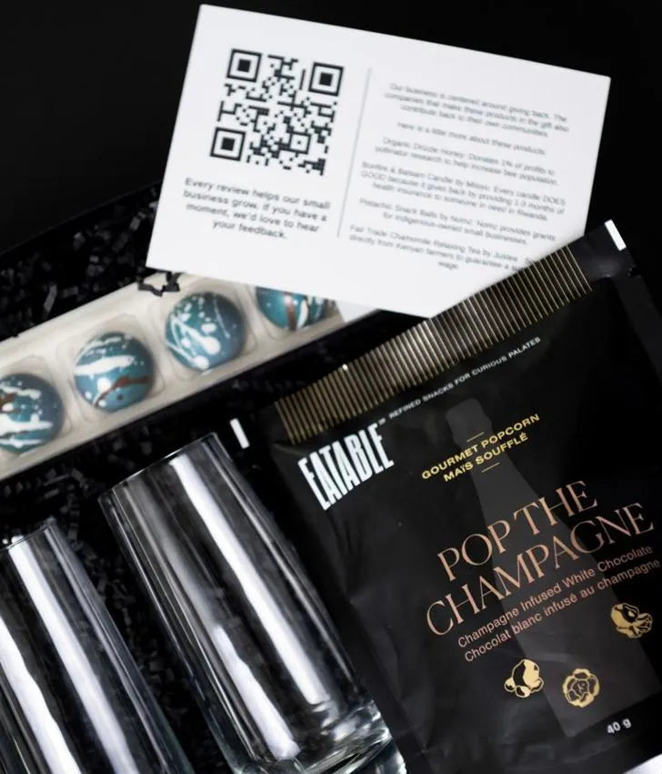An open Gray Jay gift with celebration glasses, Canadian popcorn and a personalized message card
